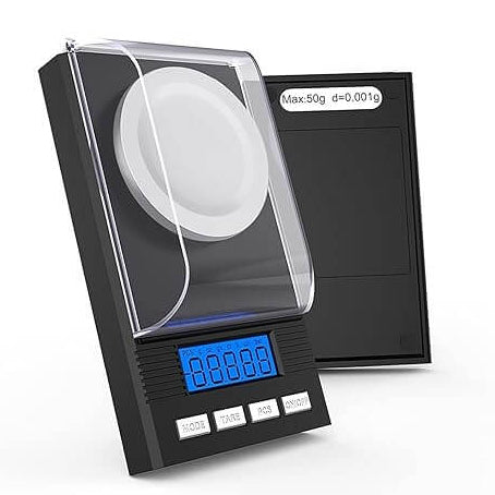 Digitale weegschaal met windkap in open positie; label toont maximale capaciteit van 50 gram en nauwkeurigheid van 0,001 gram.